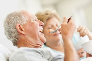 Ein älterer Herr isst Pudding und ist glücklich