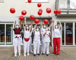 Pfleger*innen werfen Ballons vor dem Eingang in die Luft
